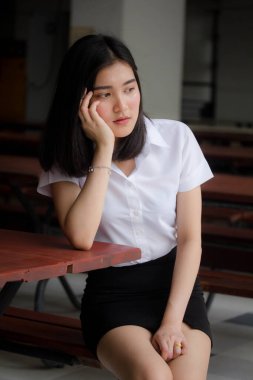 Taylandlı yetişkin öğrenci üniforması portresi. Güzel kız rahatla ve gülümse.