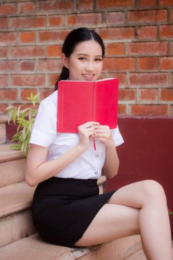 Taylandlı yetişkin öğrenci üniforması portresi. Güzel kız kırmızı kitabı okudu.