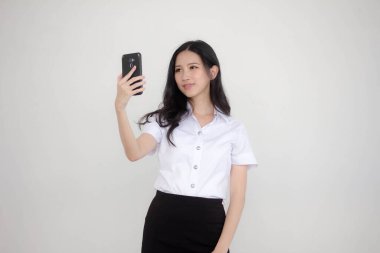 Taylandlı yetişkin öğrenci üniformasının portresi. Güzel kız akıllı telefonuyla selfie çekiyor.