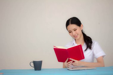 Taylandlı yetişkin öğrenci üniforması portresi. Güzel kız kırmızı kitabı okudu.