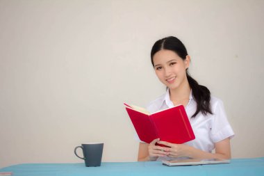 Taylandlı yetişkin öğrenci üniforması portresi. Güzel kız kırmızı kitabı okudu.