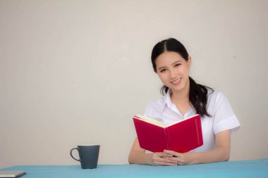 Taylandlı yetişkin öğrenci üniforması portresi. Güzel kız kırmızı kitabı okudu.