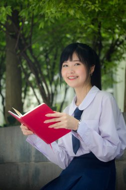 Asya Taylandlı lise öğrencisi üniforması. Güzel kız bir kitap okumuş.