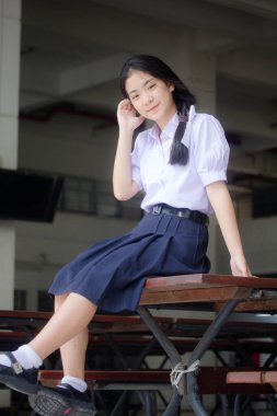 Taylandlı liseli üniformasının portresi. Genç güzel kız mutlu ve rahat.