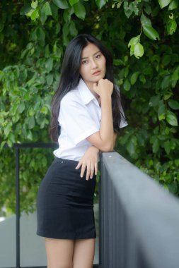 Taylandlı yetişkin öğrenci üniforması portresi. Güzel kız rahatla ve gülümse.