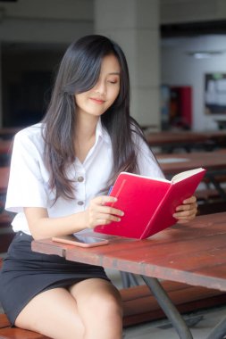 Taylandlı yetişkin öğrenci üniforması portresi. Güzel kız kırmızı kitabı okudu.