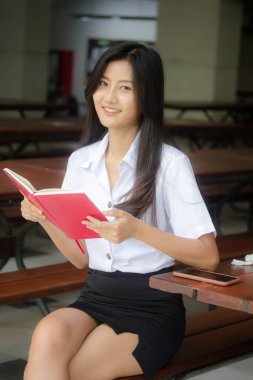 Taylandlı yetişkin öğrenci üniforması portresi. Güzel kız kırmızı kitabı okudu.