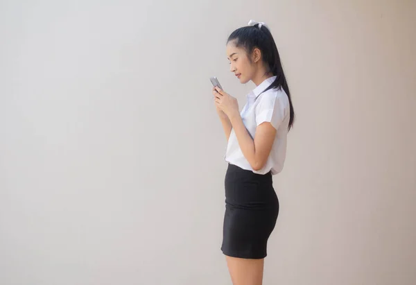 泰族成人大学生制服漂亮姑娘用智能手机的肖像 — 图库照片