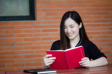 Taylandlı yetişkin öğrenci üniforması portresi. Güzel kız kırmızı kitabı okudu.