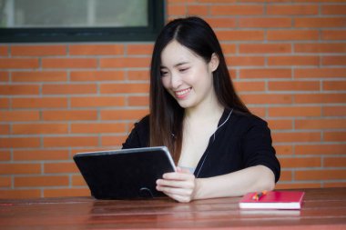 Taylandlı yetişkin öğrenci üniforması tabletini kullanan güzel bir kızın portresi..