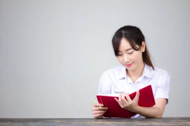 Asya Taylandlı lise öğrencisi üniforması. Güzel kız bir kitap okumuş.