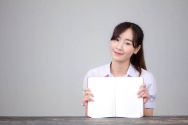 Asya Taylandlı lise öğrencisi üniforması. Güzel kız bir kitap okumuş.