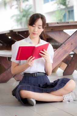 Asya Taylandlı lise öğrencisi üniforması. Güzel kız bir kitap okumuş.