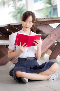 Asya Taylandlı lise öğrencisi üniforması. Güzel kız bir kitap okumuş.