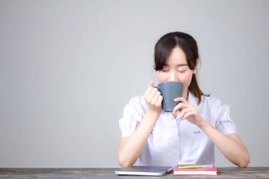 Asya Taylandlı lise öğrencisi üniforması. Güzel kız kahve içiyor.