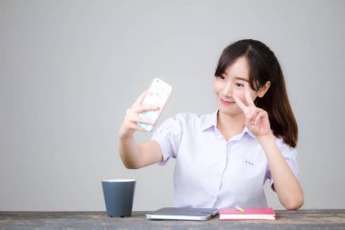 Taylandlı liseli üniformasının portresi. Güzel kız akıllı telefonuyla selfie çekiyor.