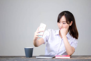 Taylandlı liseli üniformasının portresi. Güzel kız akıllı telefonuyla selfie çekiyor.
