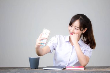 Taylandlı liseli üniformasının portresi. Güzel kız akıllı telefonuyla selfie çekiyor.