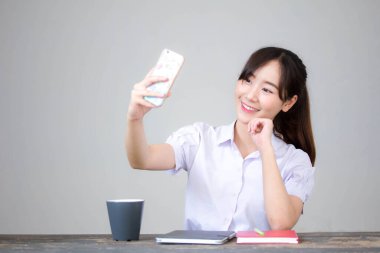 Taylandlı liseli üniformasının portresi. Güzel kız akıllı telefonuyla selfie çekiyor.