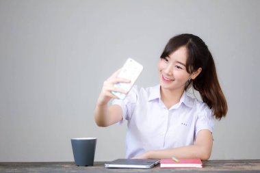 Taylandlı liseli üniformasının portresi. Güzel kız akıllı telefonuyla selfie çekiyor.