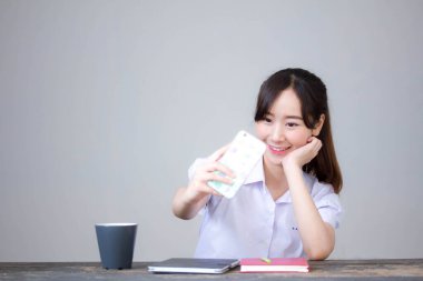 Taylandlı liseli üniformasının portresi. Güzel kız akıllı telefonuyla selfie çekiyor.