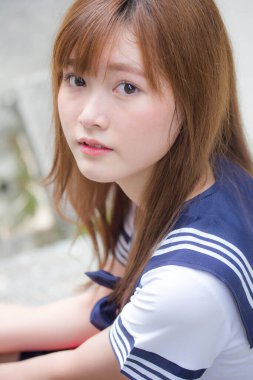 Taylandlı genç kız portresi Japon öğrenci üniforması içinde mutlu ve rahatlamış.