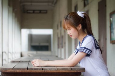 Taylandlı genç kız portresi Japon öğrenci üniforması içinde mutlu ve rahatlamış.