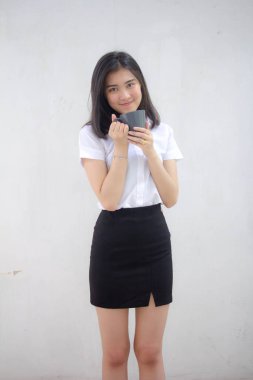 Taylandlı yetişkin öğrenci üniformasının portresi. Güzel kahve içiyor.