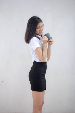 Taylandlı yetişkin öğrenci üniformasının portresi. Güzel kahve içiyor.