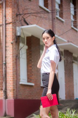 Taylandlı yetişkin öğrenci üniforması portresi. Güzel kız rahatla ve gülümse.