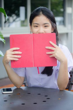Asya Taylandlı lise öğrencisi üniforması. Güzel kız bir kitap okumuş.