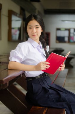 Asya Taylandlı lise öğrencisi üniforması. Güzel kız bir kitap okumuş.
