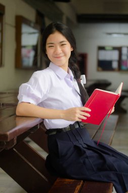 Asya Taylandlı lise öğrencisi üniforması. Güzel kız bir kitap okumuş.
