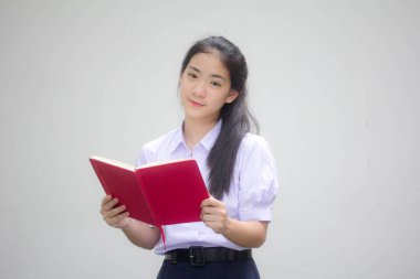 Asya Taylandlı lise öğrencisi üniforması. Güzel kız bir kitap okumuş.