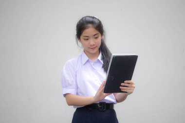 Portrait of thai high school student uniform beautiful girl using her tablet