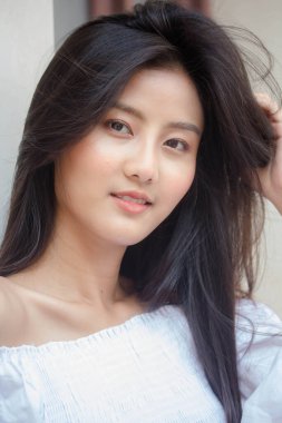 Taylandlı yetişkin güzel kız portresi. Beyaz gömlek, mavi kot pantolon, rahatla ve gülümse.