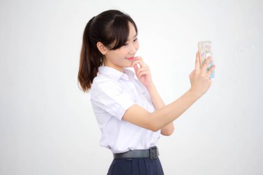 Taylandlı liseli üniformasının portresi. Güzel kız akıllı telefonuyla selfie çekiyor.