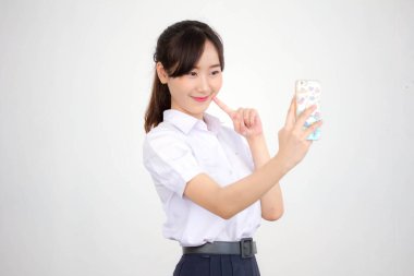 Taylandlı liseli üniformasının portresi. Güzel kız akıllı telefonuyla selfie çekiyor.