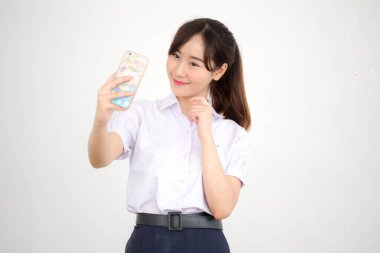 Taylandlı liseli üniformasının portresi. Güzel kız akıllı telefonuyla selfie çekiyor.
