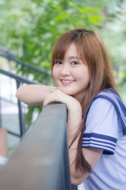 Taylandlı genç kız portresi Japon öğrenci üniforması içinde mutlu ve rahatlamış.