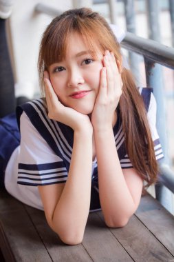 Taylandlı genç kız portresi Japon öğrenci üniforması içinde mutlu ve rahatlamış.