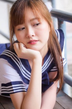 Taylandlı genç kız portresi Japon öğrenci üniforması içinde mutlu ve rahatlamış.
