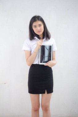 Taylandlı yetişkin öğrenci üniforması tabletini kullanan güzel bir kızın portresi..