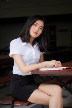 Taylandlı yetişkin öğrenci üniforması portresi. Güzel kız rahatla ve gülümse.