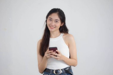 Tayland portresi. Yetişkin, güzel bir kız. Akıllı telefonunu kullanan beyaz gömlek, mavi kot pantolon.