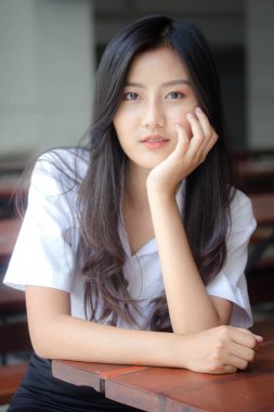 Taylandlı yetişkin öğrenci üniforması portresi. Güzel kız rahatla ve gülümse.