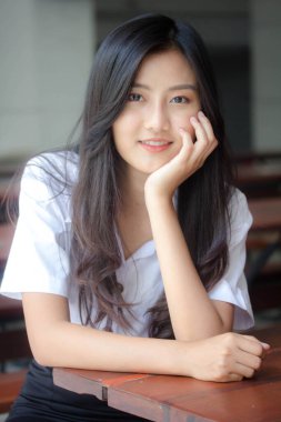 Taylandlı yetişkin öğrenci üniforması portresi. Güzel kız rahatla ve gülümse.