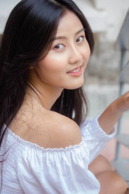 Taylandlı yetişkin güzel kız portresi. Beyaz gömlek, mavi kot pantolon, rahatla ve gülümse.