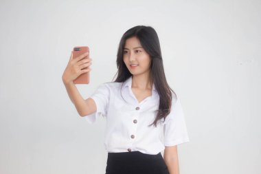 Taylandlı yetişkin öğrenci üniformasının portresi. Güzel kız akıllı telefonuyla selfie çekiyor.