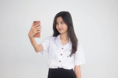 Taylandlı yetişkin öğrenci üniformasının portresi. Güzel kız akıllı telefonuyla selfie çekiyor.